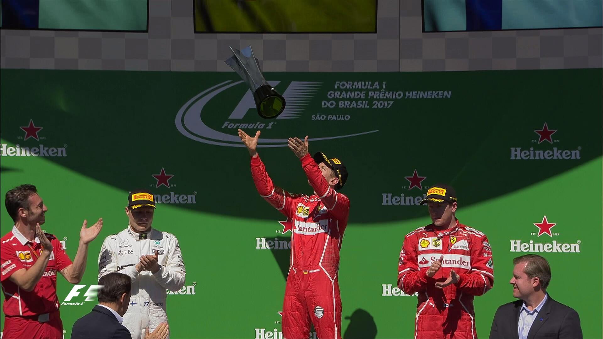 Sebastian Vettel melempar piala juara GP Brasil.