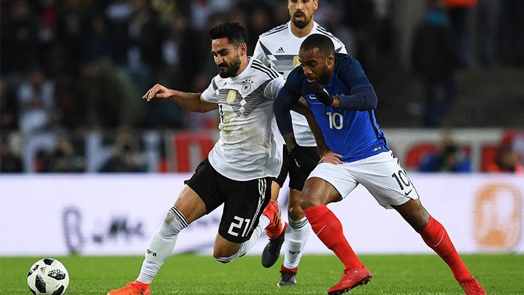 Aksi Alexandre Lacazette saat berebut bola dengan Ilkay Gundogan. Copyright: DFB