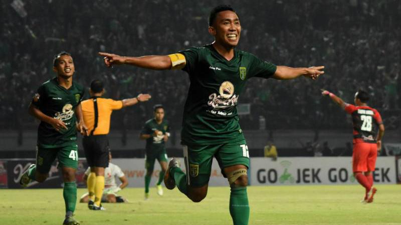 Gelandang Persebaya, Rendi Irawan, merayakan gol yang ia cetak pada malam hari.
