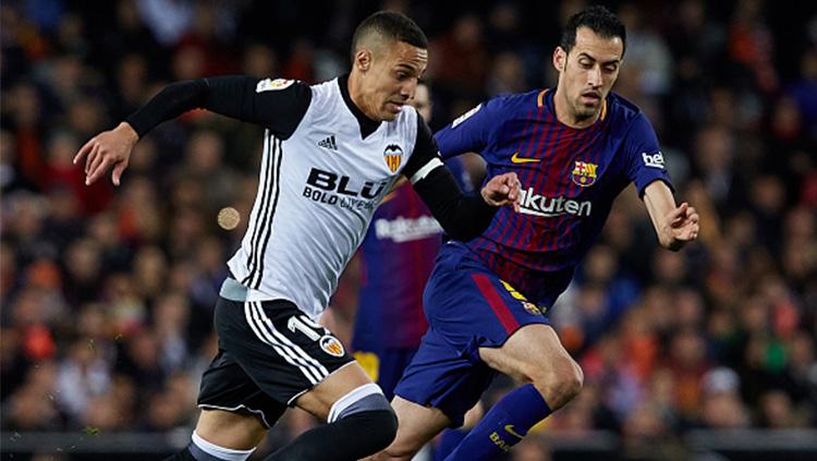 Rodrigo Moreno (Valencia) berjibaku dengan Sergio Busquets. Copyright: INDOSPORT