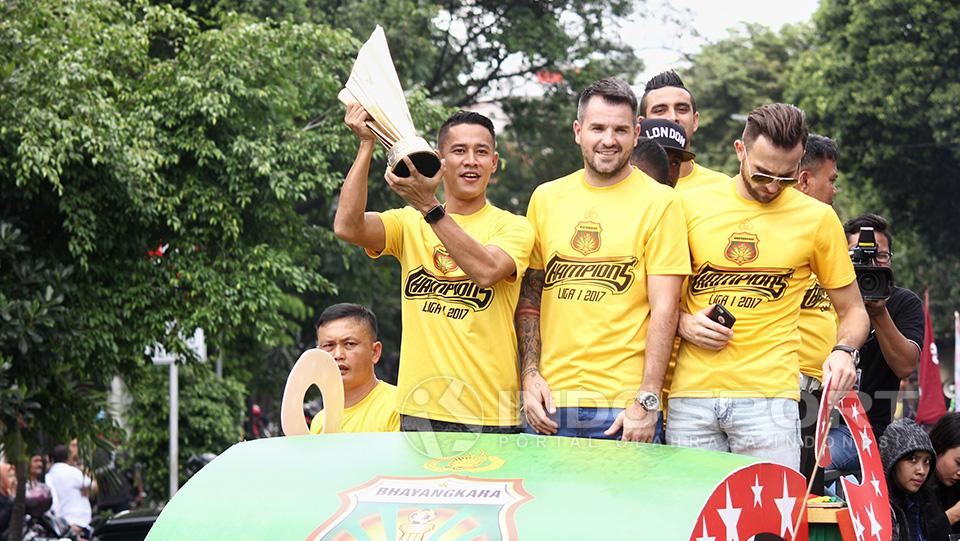 Indra Kahfi dengan bangga mengangkat trofi juara Liga 1 di atas mobil pawai.