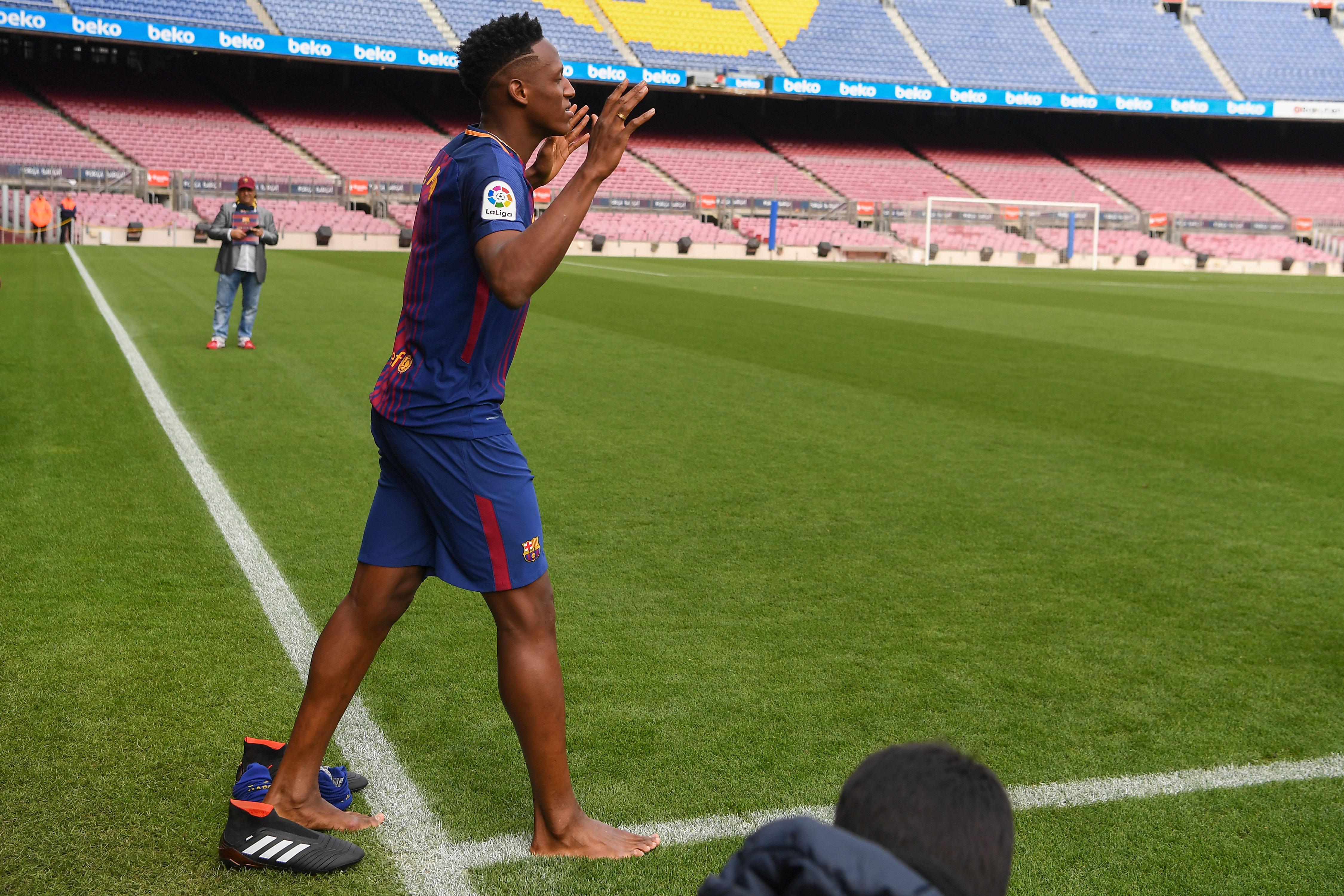 Yerry Mina melepas sepatunya saat pertama kali menginjak rumput Stadion Camp Nou. Copyright: INDOSPORT