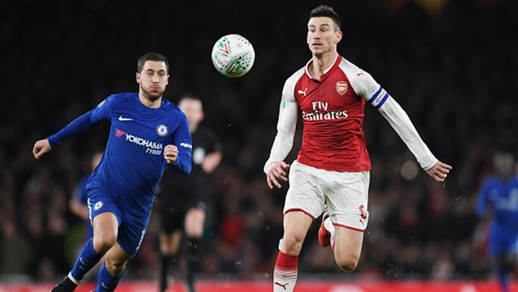 Laurent Koscielny dan Eden Hazard tampak berusaha mengambil bola.