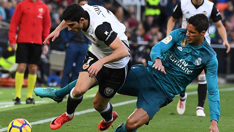 Raphael Varane (kanan) berebut bola dengan pemain Valencia. Copyright: INDOSPORT