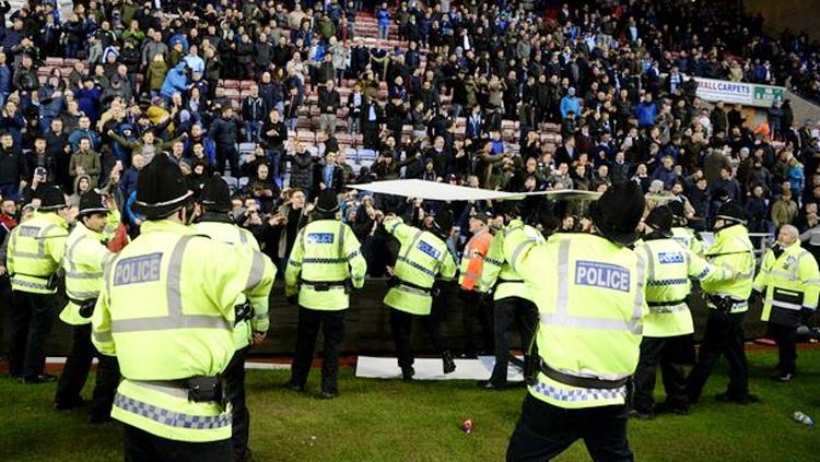 Suporter Wigan Athletic melemparkan papan iklan ke arah polisi atau ke dalam lapangan. - INDOSPORT