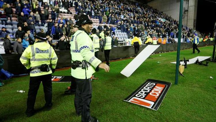 Suporter Wigan Athletic melemparkan papan iklan ke arah polisi atau ke dalam lapangan. Copyright: INDOSPORT