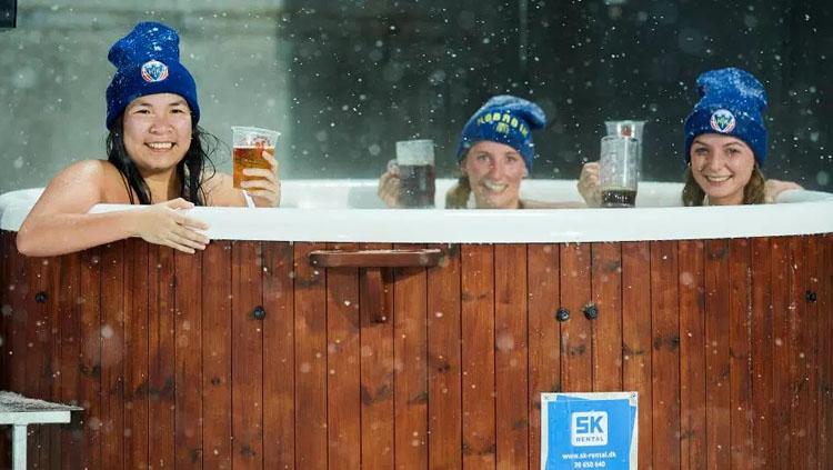 Tiga wanita cantik menonton laga Liga Denmark sembari berendam di pinggir lapangan. Copyright: Getty Images.