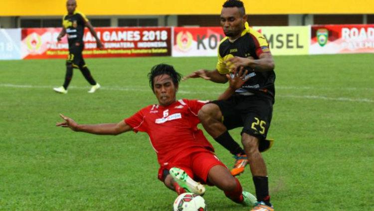 Erwin Gutawa merebut bola dari penyerang Sriwijaya Titus Bonai. Copyright: BanjarmasinPost