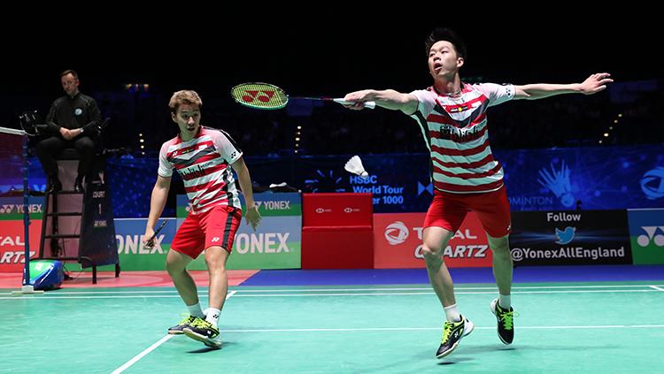 Kevin Sanjaya (kanan) berusaha meraih shuttlecock saat bermain di final All England 2018