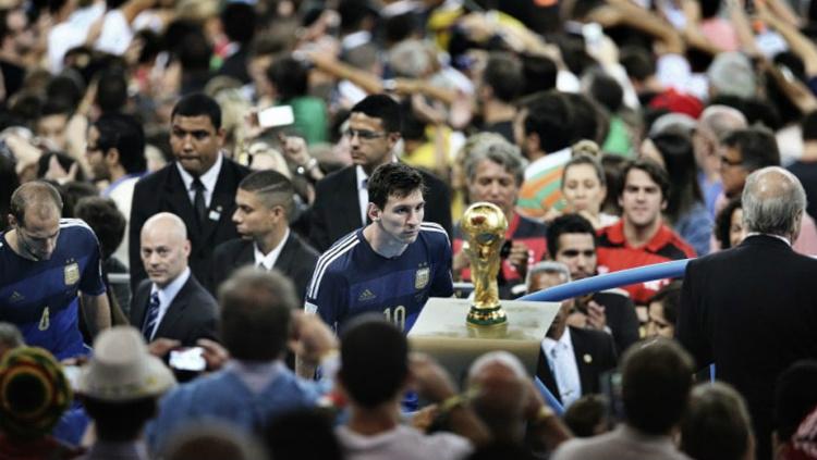 Messi berjalan melewati trofi Piala Dunia di tahun 2014.