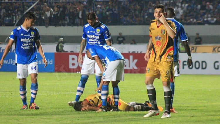 Salah satu pemain Mitra Kukar terdampar di tanah setelah kalah adu body dengan pemain Persib.