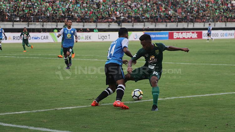 Pemain Persebaya dan Barito Putera tengah saling berusaha merebut bola.
