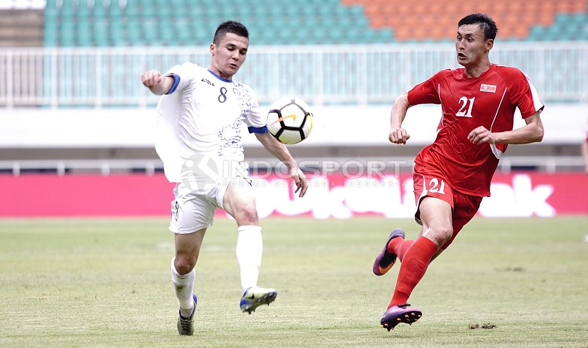 Pemain Uzbekistan, Kenjabaev Islom (kiri) memcoba melewati pemain Korut, Kim Nam II. Herry Ibrahim/INDOSPORT. Copyright: Herry Ibrahim/INDOSPORT