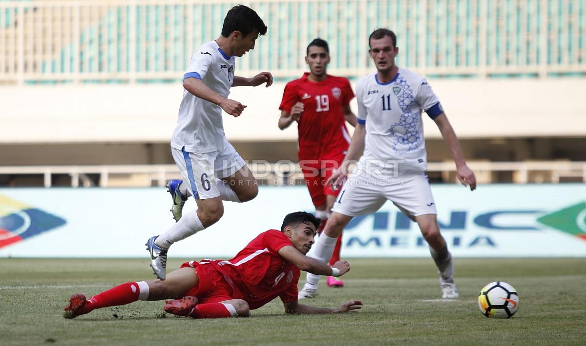 Pemain Bahrain (bawah) mencoba menghalangi pergerakan pemain Uzbekistan, Nurulloev Sukhrob. Herry Ibrahim