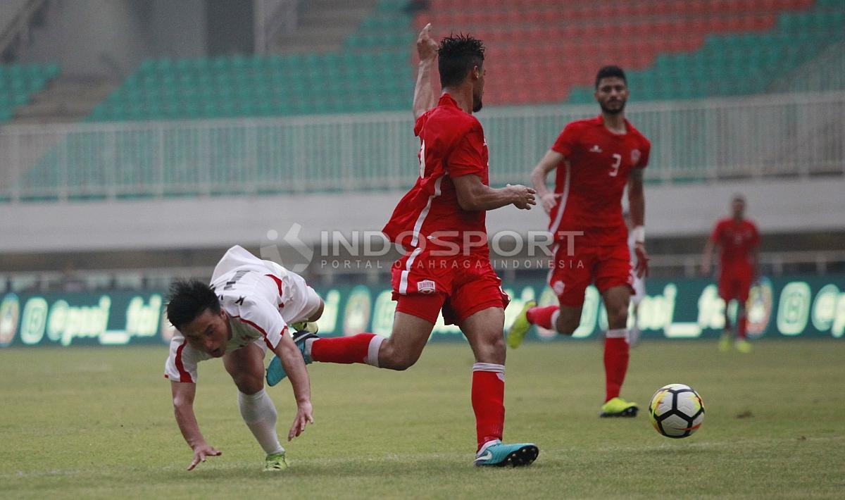 Pemain Korea Utara (kiri) terjatuh saat gagal melewati pemain Bahrain. Herry Ibrahim