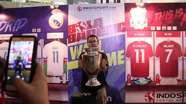 Seorang fans berfoto dengan replika trofi Liga Champions.