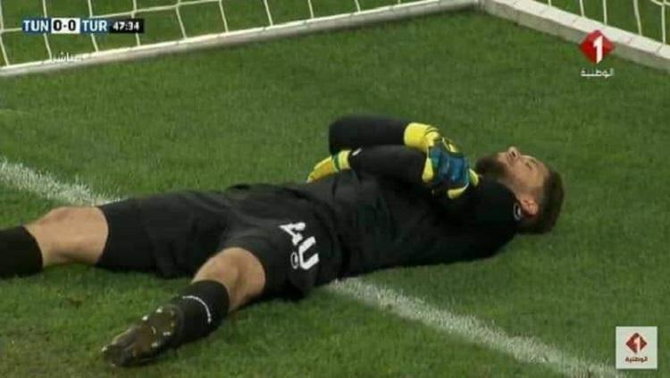 Kiper Timnas Tunisia, Mouez Hassen tertangkap kamera berpura-pura cedera demi berbuka puasa di laga uji coba melawan Turki, Sabtu (02/06/18). - INDOSPORT