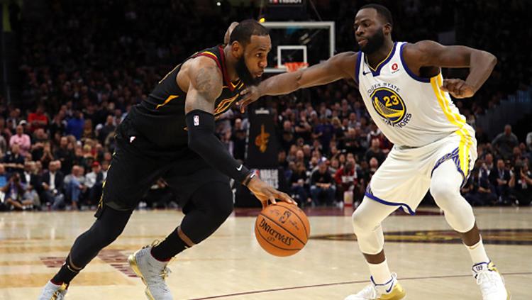 Draymond Green (kanan) berusaha menghentikan aksi LeBron James.