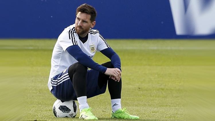Lionel Messi mengisi waktu istirahatnya dengan duduk di atas bola.