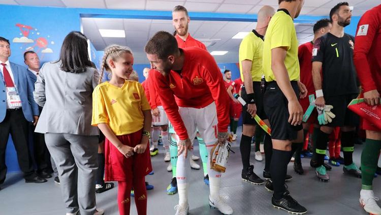 Kapten Spanyol, Sergio Ramos, berbincang dengan maskot cilik di lorong stadion jelang laga perdana menghadapi Portugal.