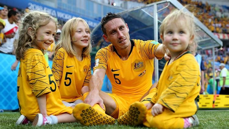 Bek Timnas Australia, Mark Milligan, sedang bercengkrama bersama putri-putrinya tercinta di tepi lapangan. Copyright: fifa.com