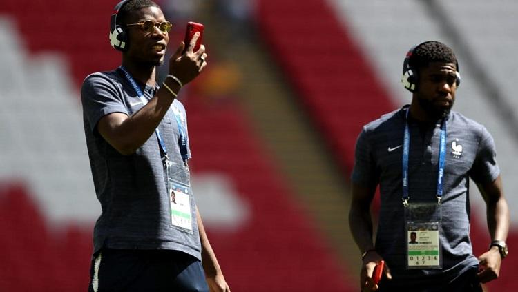 Gelandang Prancis, Paul Pogba, mencek smartphone-nya jelang laga perdana menghadapi Australia di Kazan Arena.