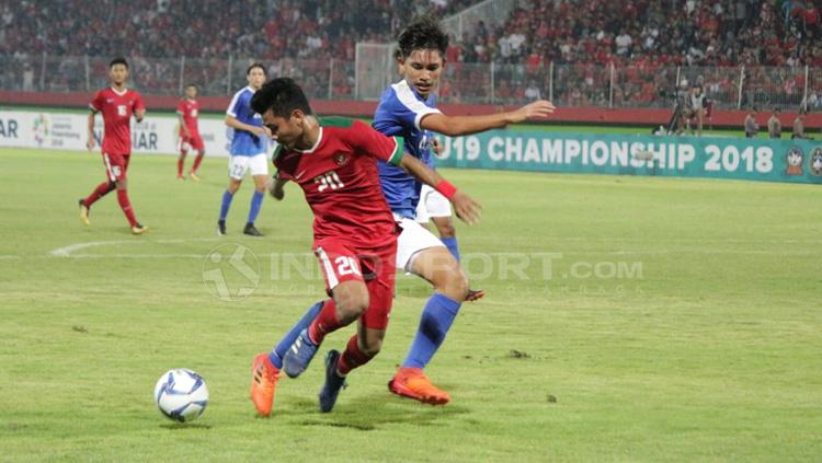 Asnawi Mangkualam duel dengan pemain Singapura U-19 untuk mendapatkan bola.