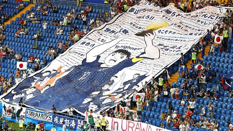Fans Jepang membentangkan spanduk tokoh kartun dari negara mereka yang sudah terkenal di dunia, yakni Captain Tsubasa yang memegang trofi Piala Dunia. Harapannya jelas agar negara kesayangan mereka dapat bisa menjadi juara dunia.