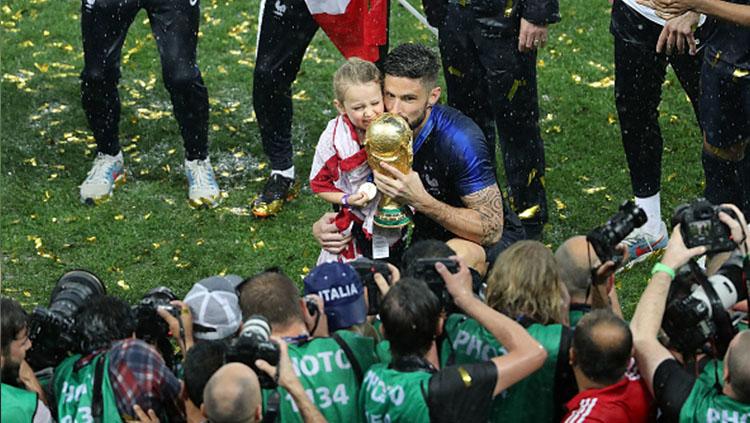 Olivier Giroud bersama putrinya memegang trofi emas Piala Dunia.