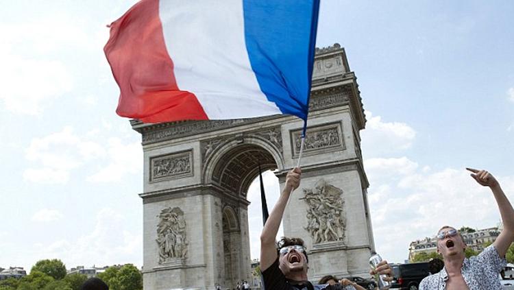 Penggemar Prancis mengibarkan bendera di luar Arc de Triomphe.