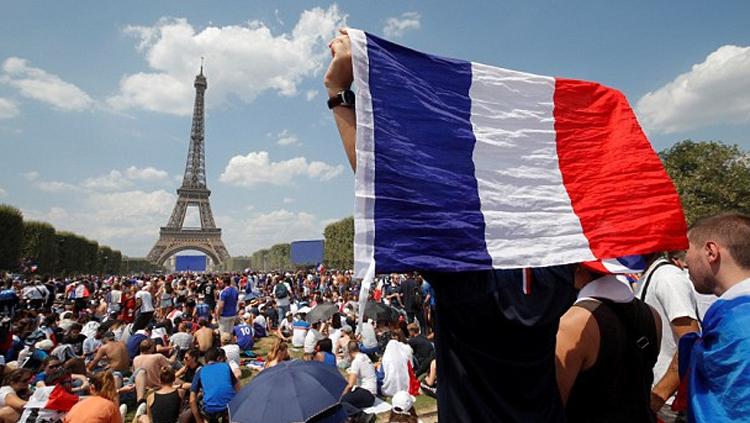 Seorang pendukung Prancis memperkenalkan bendera mereka dengan menghadap ke menara Eiffel.