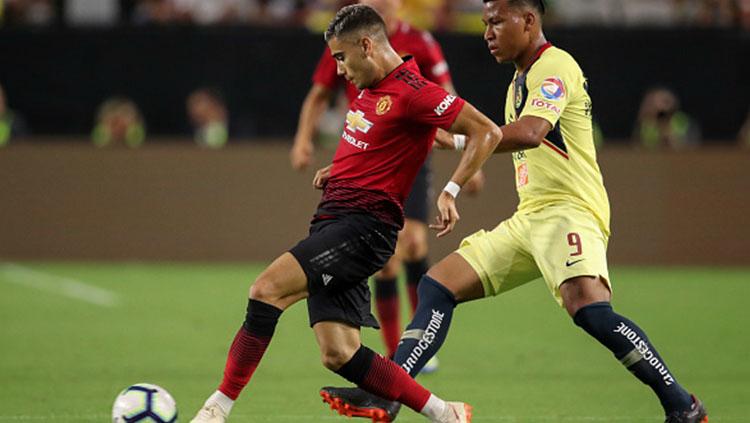 Andreas Pereira mengontrol bola dan Roger Martinez berusaha mengagalkannya.