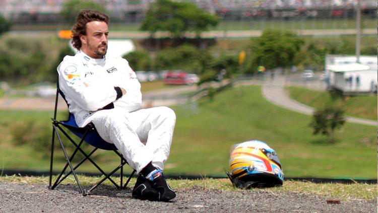 Fernando Alonso, pembalap F1 sedang duduk santai di pinggir Sirkuit Yas Marina, Abu Dhabi. - INDOSPORT