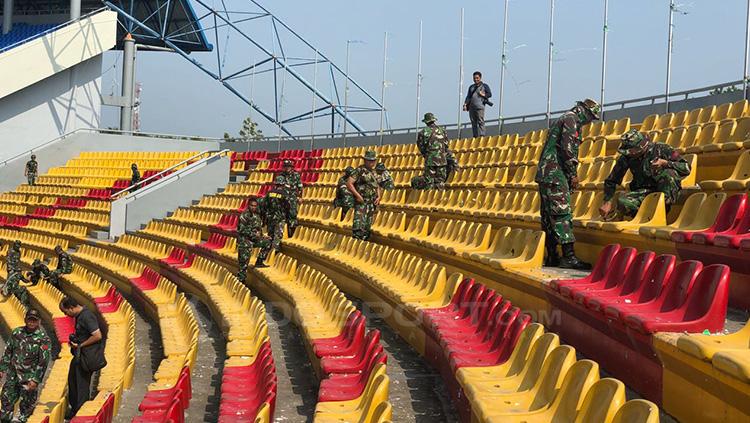 Prajurit TNI tangah membereskan kursi yang rusak ulah dari suporter. Copyright: Muhammad Effendi/INDOSPORT