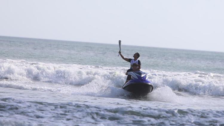 Hamish Daud berselancar dengan membawa obor Asian Games 2018 di Pantai Kuta, Bali.