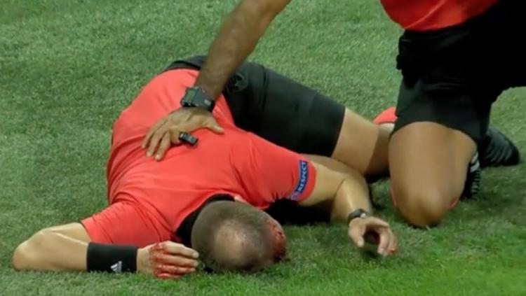 Wasit sepakbola tergeletak usai terkena lemparan batu. - INDOSPORT