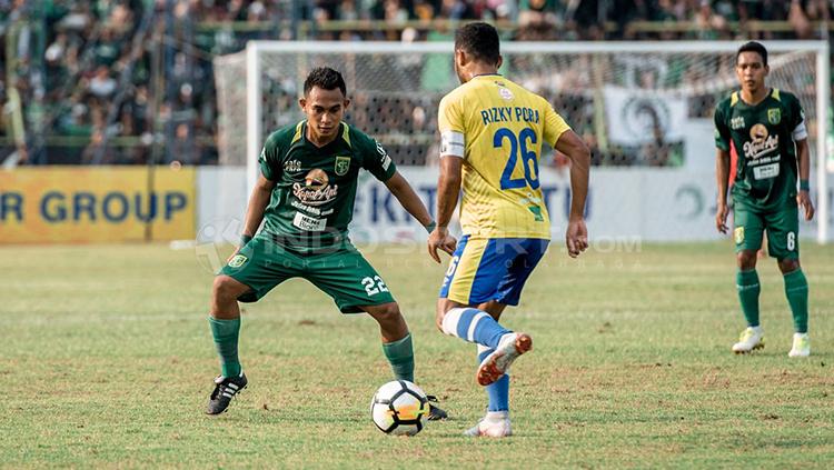 Rizky Pora berusaha melewati pemain persebaya Adam Maulana.