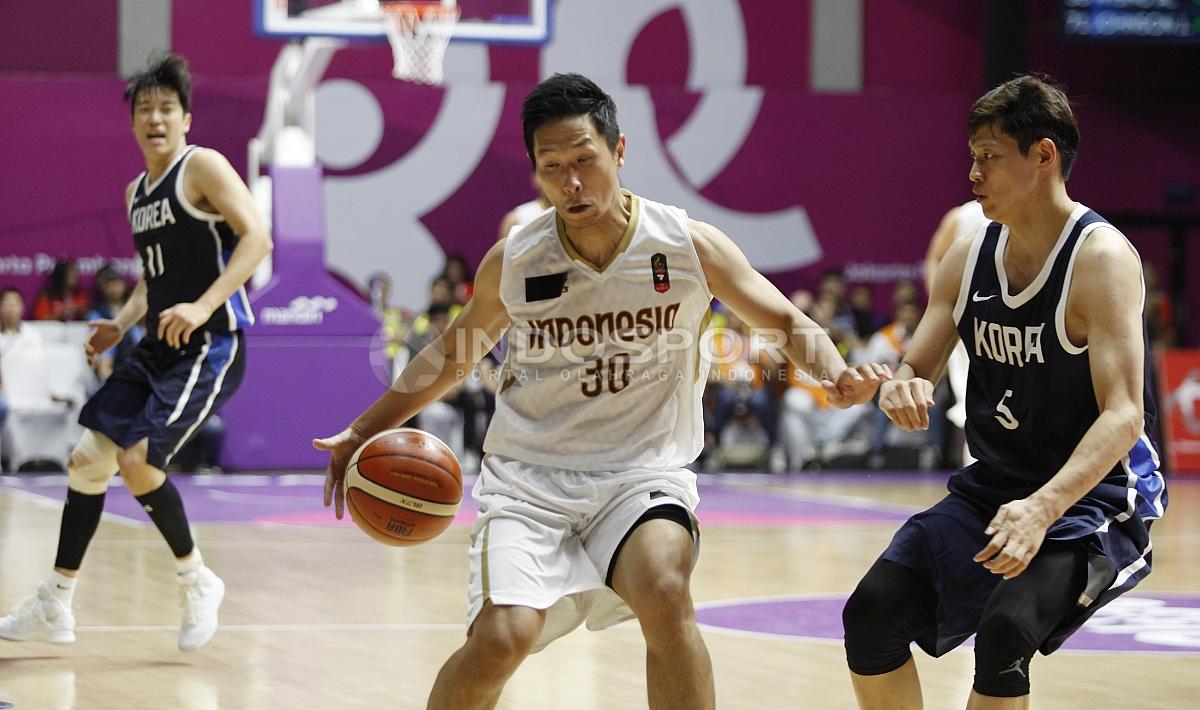 Aksi pebasket Indonesia, Xaverius Prawiro mendrible bola melewati hadangan pemain Korea, Kim Sunhyung (kanan).