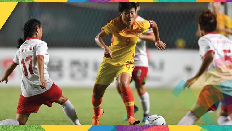 Pemain timnas Cina putri (kuning) membawa bola dan dikawal ketat pemain Tajikistan.