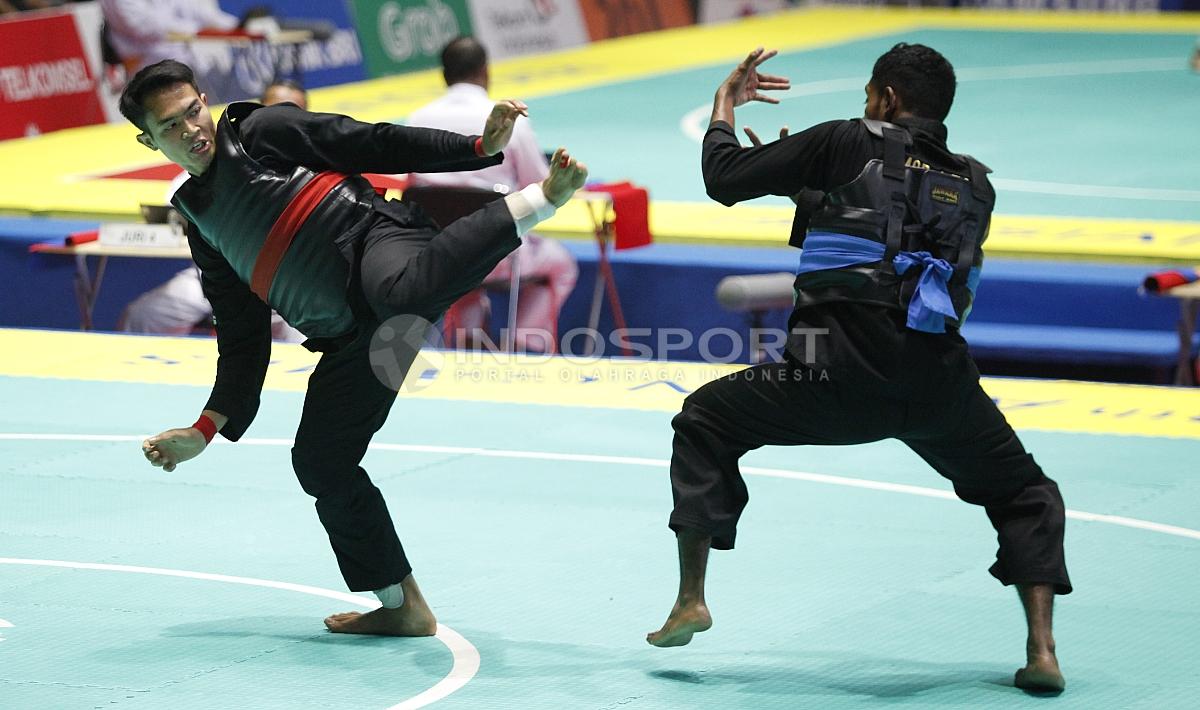 Pesilat Indonesia, Komang Adi Putra (sabuk merah) melawan Pesilat Timor Leste (sabuk biru) pada babak 16 besar Kelas E Putra 65 kg-70kg di Padepokan Pencak Silat TMII, Rabu (23/08/18). Komang menang telak 5 poin atas lawannya.