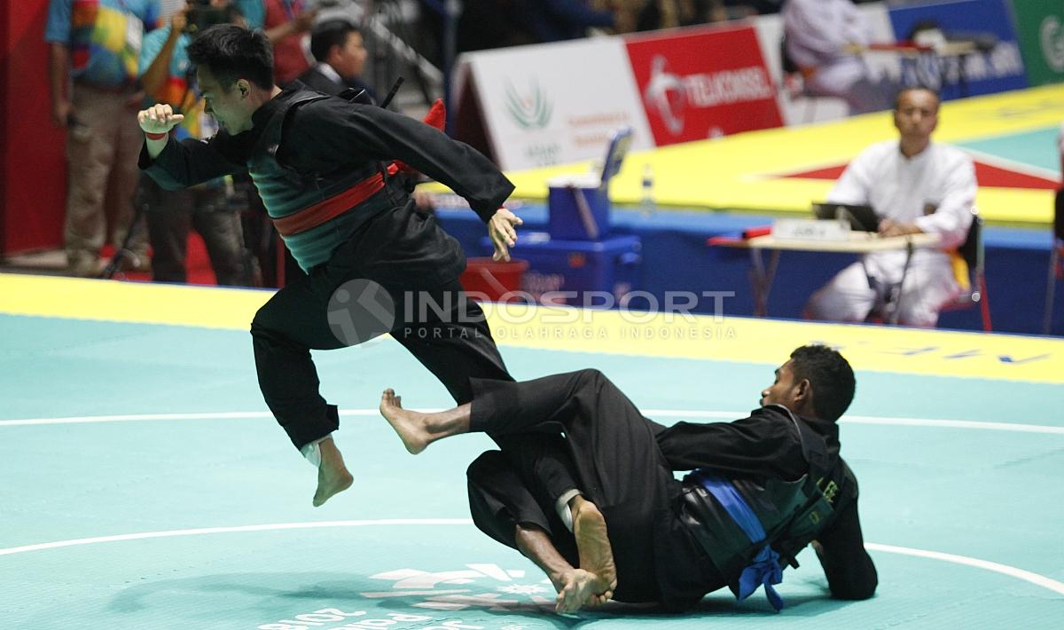 Pesilat Indonesia, Komang Adi Putra (sabuk merah) melawan Pesilat Timor Leste (sabuk biru) pada babak 16 besar Kelas E Putra 65 kg-70kg di Padepokan Pencak Silat TMII, Rabu (23/08/18). Komang menang telak 5 poin atas lawannya.