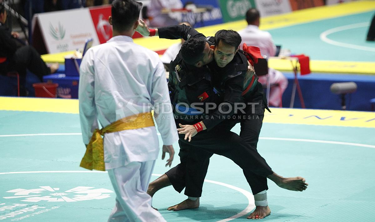 Pesilat Indonesia, Komang Adi Putra (sabuk merah) melawan Pesilat Timor Leste (sabuk biru) pada babak 16 besar Kelas E Putra 65 kg-70kg di Padepokan Pencak Silat TMII, Rabu (23/08/18). Komang menang telak 5 poin atas lawannya.