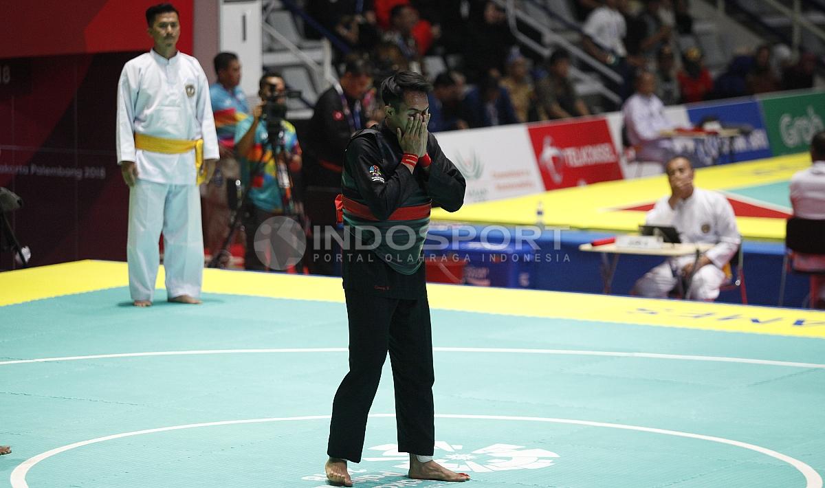 Pesilat Indonesia, Komang Adi Putra (sabuk merah) melawan Pesilat Timor Leste (sabuk biru) pada babak 16 besar Kelas E Putra 65 kg-70kg di Padepokan Pencak Silat TMII, Rabu (23/08/18). Komang menang telak 5 poin atas lawannya.