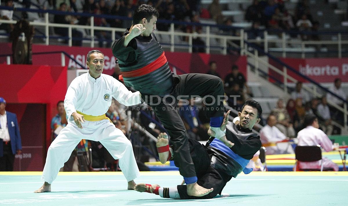 Pesilat Indonesia, Amri Rusdana (sabuk biru) melawan Pesilat Uzbekistan, Nurulla Saidov pada babak 16 besar Kelas F Putra 70kg-75kg di Padepokan Pencak Silat TMII, Rabu (23/08/18). Amri menang 5-0 atas lawannya.