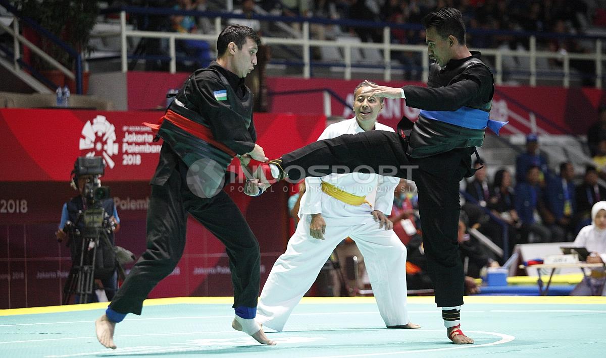 Pesilat Indonesia, Amri Rusdana (sabuk biru) melawan Pesilat Uzbekistan, Nurulla Saidov pada babak 16 besar Kelas F Putra 70kg-75kg di Padepokan Pencak Silat TMII, Rabu (23/08/18). Amri menang 5-0 atas lawannya.