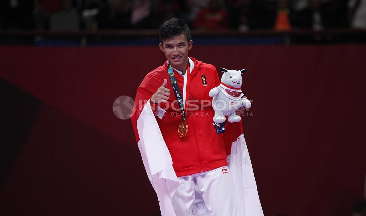 Atlet Karate Indonesia, Rifki Ardian Arrosyid memperlihatkan medali emasnya usai penganugerahan juara Karate Putra -60kg di Plenary Hall JCC, Jakarta, Minggu (26/08/18).
