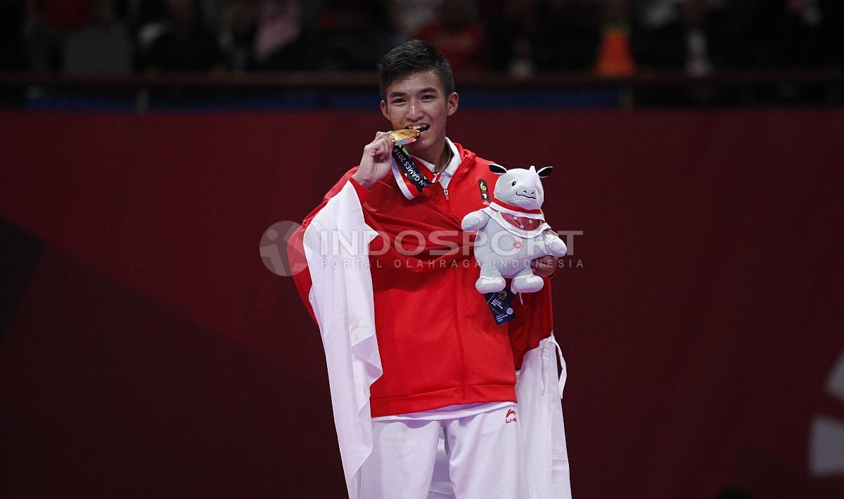 Atlet Karate Indonesia, Rifki Ardian Arrosyid memperlihatkan medali emasnya usai penganugerahan juara Karate Putra -60kg di Plenary Hall JCC, Jakarta, Minggu (26/08/18).