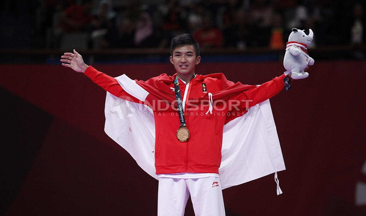 Atlet Karate Indonesia, Rifki Ardian Arrosyid memperlihatkan medali emasnya usai penganugerahan juara Karate Putra -60kg di Plenary Hall JCC, Jakarta, Minggu (26/08/18).