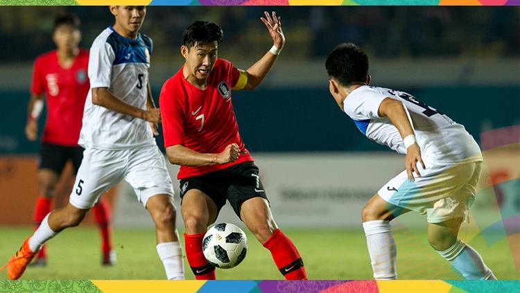 Son Heung-min (tengah) berebut bola dengan pesebak bola Kirgistan Manybekov Amanbek (kanan) saat pertandingan babak penyisihan sepak bola Grup E Asian Games 2018 di Stadion Si Jalak Harupat, Soreang, Kabupaten Bandung, Jawa Barat, Senin (20/8). Copyright: Novrian Arbi/Antara Foto/INASGOC