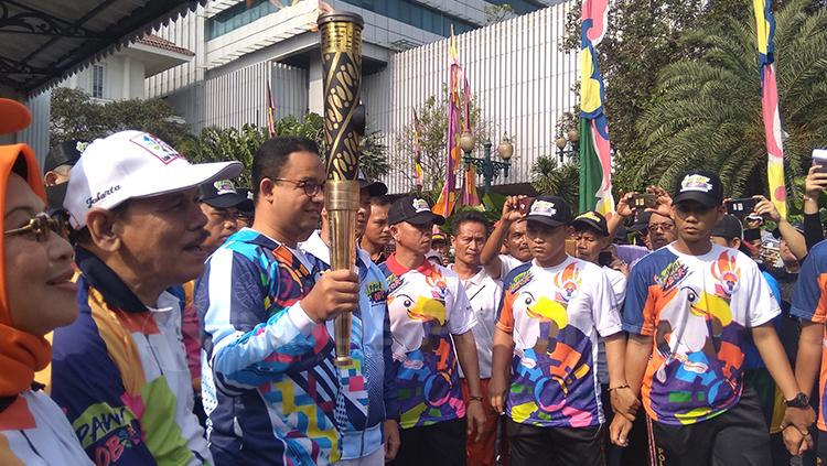 Anies Baswedan membawa obor Torch Relay Asian Para Games 2018 Jakarta.